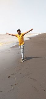 Full length of person on sand at beach against clear sky