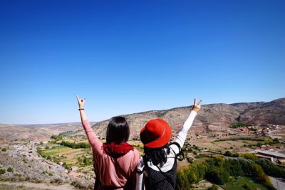 Rear view of woman photographing on landscape against clear sky