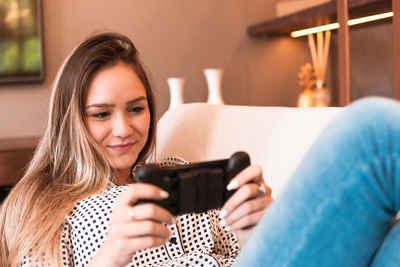 Young woman using mobile phone while sitting on sofa at home