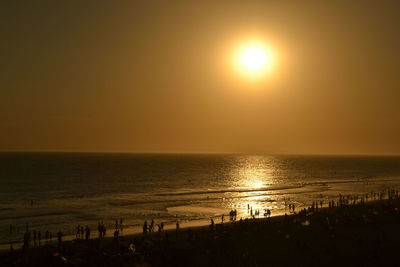 Scenic view of crowded beach and sunset over sea