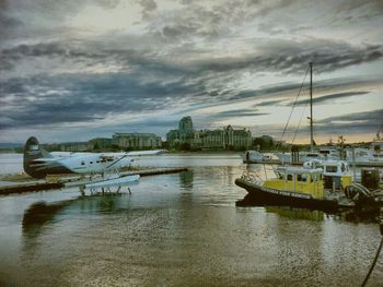 Boats in harbor against cloudy sky