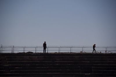 Silhouette of people standing on railing