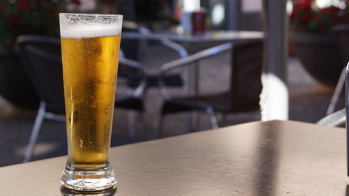 Close-up of beer glass on table at sidewalk cafe