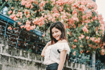 Portrait of smiling young woman standing against tree