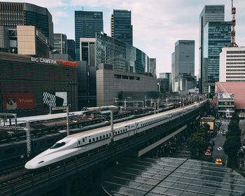 Railroad tracks amidst buildings in city against sky