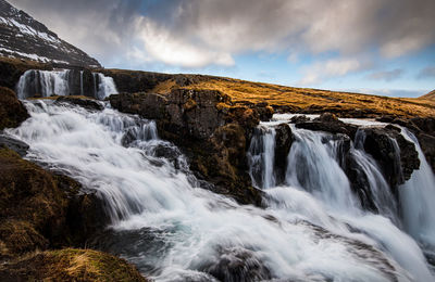 Scenic view of waterfall against sky