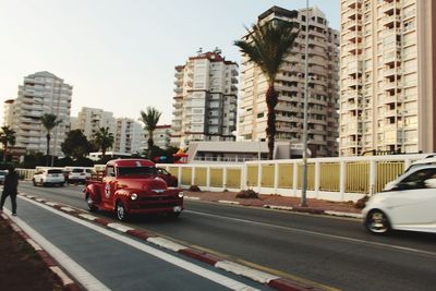 Cars on city street by buildings against sky