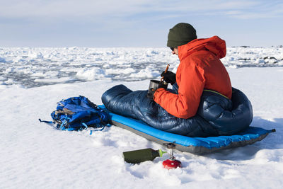 Man sitting on snow covered land