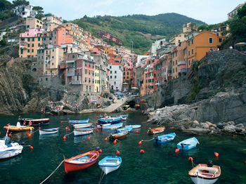 Boats moored on sea against buildings in town