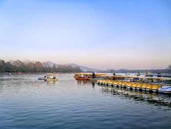 Boats moored at harbor against clear sky