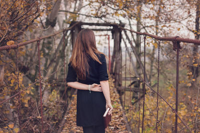 Mid adult woman with book on footbridge amidst park