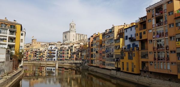 Canal amidst buildings in city against sky