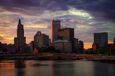 River by buildings against sky during sunset