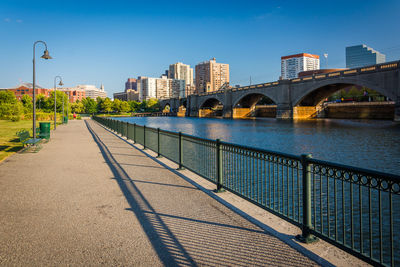 Bridge over river by buildings against sky in city