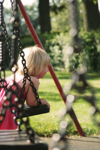Rear view of a girl on swing in park