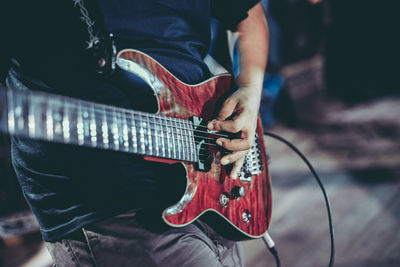 Midsection of man playing guitar