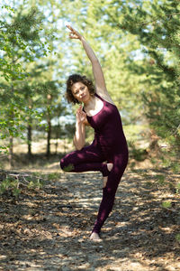 Full length of young woman jumping in forest