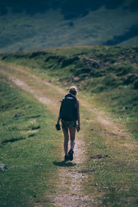 Rear view full length of female hiker walking on trail