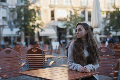 Young woman sitting on table in city