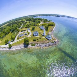 Aerial view of houses on field by sea