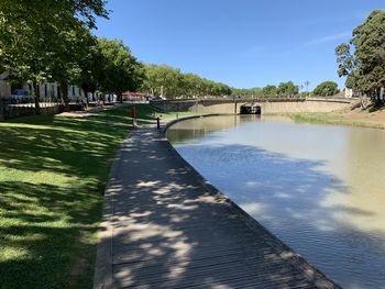 Footpath by canal against sky