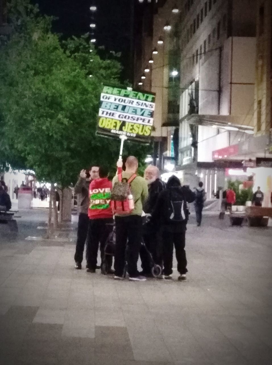 GROUP OF PEOPLE STANDING ON STREET IN CITY