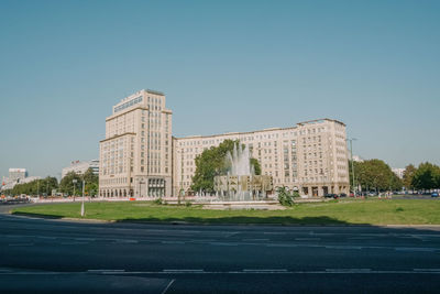 Road by building against clear blue sky