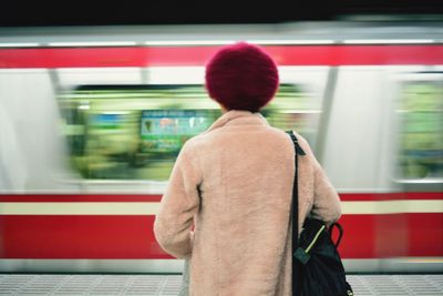 Rear view of woman standing at railroad station