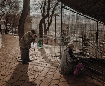 Senior man photographing woman on footpath