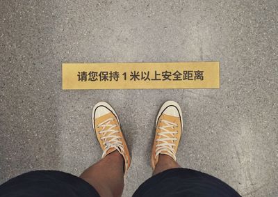 Low section of man standing by text on floor