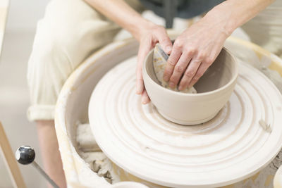 Cropped hands of potter making container at workshop