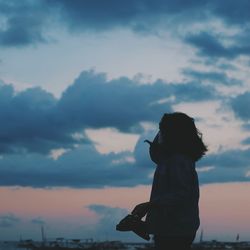 Silhouette woman standing against sky during sunset