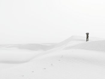 Man standing at desert against clear sky