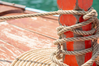 Close up the rope tied around a orange wooden pole on the boat. unity concept.