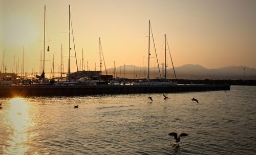 Boats moored in sea at sunset