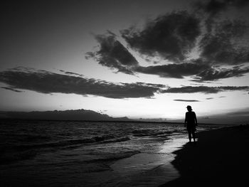 Silhouette man standing on beach against sky during sunset