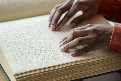 Hands of woman reading braille text from book