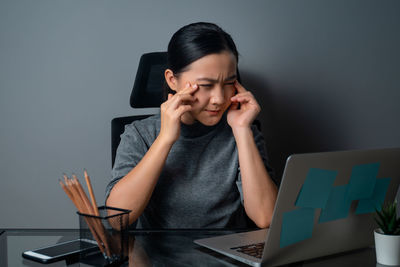 Young woman using mobile phone while sitting on table