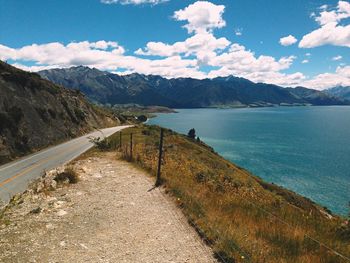 Scenic view of road by sea against sky