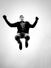 Low angle view of man jumping against clear sky