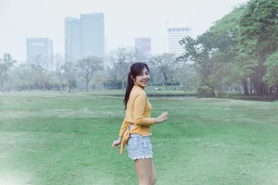 Portrait of smiling young woman standing in park