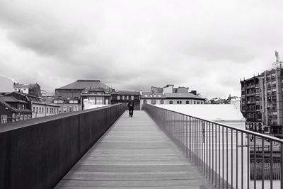 Footbridge amidst buildings in city against sky