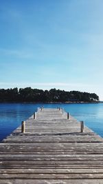 Pier over lake against clear blue sky