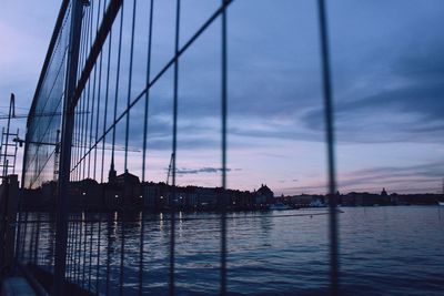 Silhouette bridge over river against sky at sunset