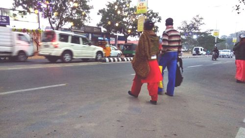 Rear view of people walking on road in city