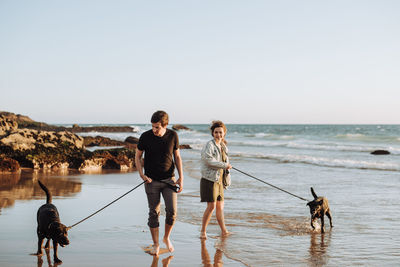 People with dog on beach against sky