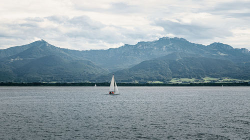 Scenic view of sailing boat and mountains against sky