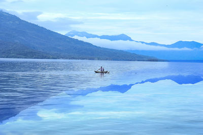 Scenic view of sea by mountains against sky