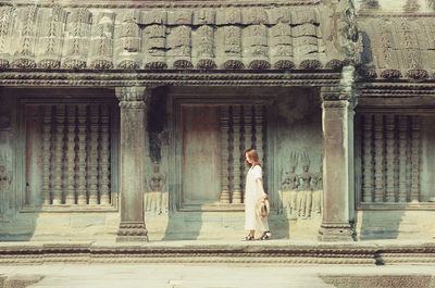 Woman standing against door of building