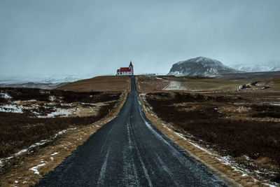 Road leading towards snowcapped mountain against sky